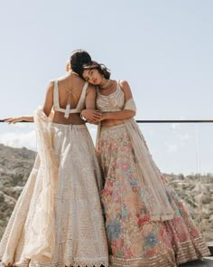 two women standing next to each other in long dresses and one is wearing a crop top