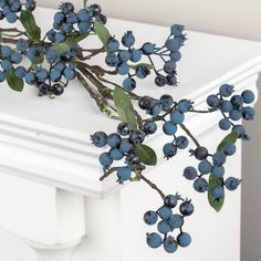 some blue berries are hanging on a white mantle