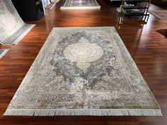 an antique rug is on the floor in a room with wooden floors and chairs around it