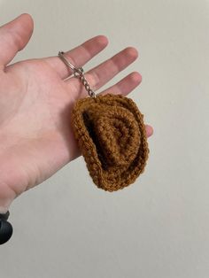 a hand holding a small brown object in it's left hand with a chain attached to it