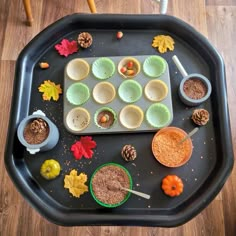 a tray filled with cupcakes on top of a wooden table covered in leaves