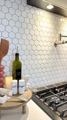 a stove top oven sitting inside of a kitchen next to a wooden spoon and bottle