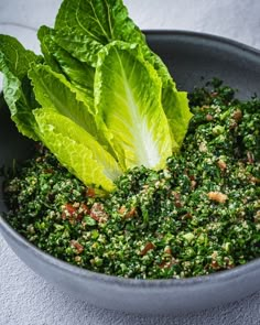 a bowl filled with lettuce and other vegetables on top of a white table