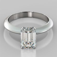 an emerald cut diamond engagement ring on a white background