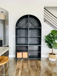 a large bookcase in the middle of a room with wooden floors and white walls