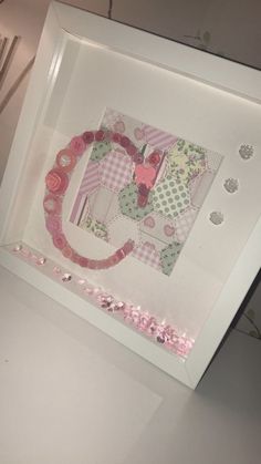 an art piece is displayed in a white frame with pink flowers on the bottom and sides