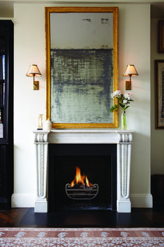 a living room filled with furniture and a fire place covered in a large framed painting