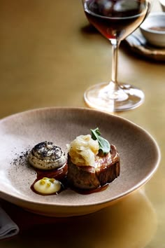 a plate with some food on it next to a glass of red wine and two glasses of wine