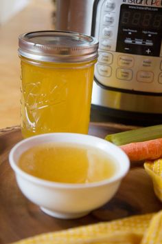 a bowl of soup sits next to an instant pot and some corn on the cob