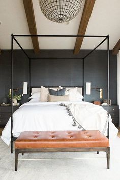 a bedroom with a four poster bed and wooden beams on the ceiling, along with a bench in front of it