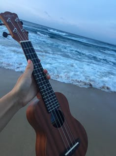 a person is holding an ukulele on the beach