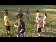 a group of people standing on top of a grass covered field next to each other