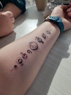 a person sitting at a table with a tattoo on their arm that reads, solar system