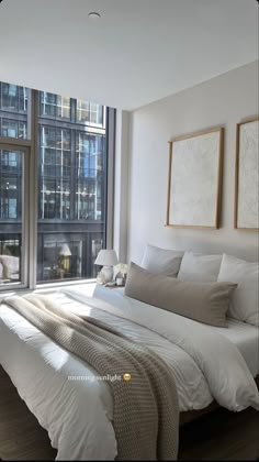 a large bed sitting in front of a window next to a wall mounted art piece