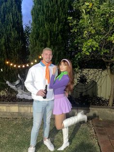 a man and woman dressed up in costume posing for a photo together outside at night