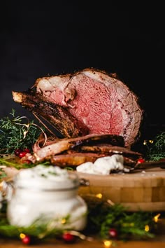 a roast beef on a cutting board surrounded by christmas greenery and other holiday foods