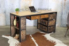 a wooden desk with drawers and a laptop computer on it, in front of a rusty wall