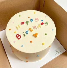 a birthday cake with the words happy birthday written on it sitting in a cardboard box