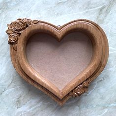 a wooden heart shaped frame with roses on it