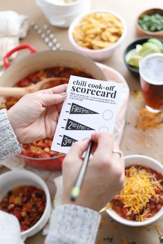 a person is holding a card over some bowls of food