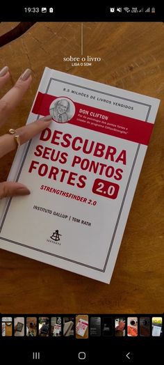 a person pointing at a book on top of a wooden table