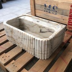 a marble sink sitting on top of wooden pallets