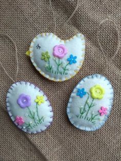 three handmade buttons with flowers on them sitting on a piece of fabric next to some thread