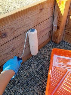 a person in blue gloves is painting a wooden fence