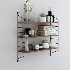 three shelves with books, vases and plants on them