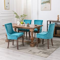 a dining room table with blue chairs and a rug on the floor in front of it