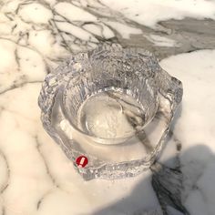 an empty glass bowl sitting on top of a marble table covered in snow and ice