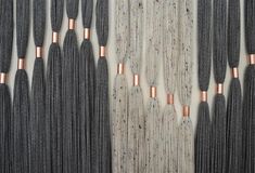 several rows of black and rose gold fringes hanging on a white wall with wood flooring