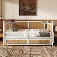 a white bed sitting on top of a wooden floor next to a painting above it