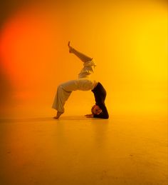 a person doing a handstand on the floor in front of an orange background