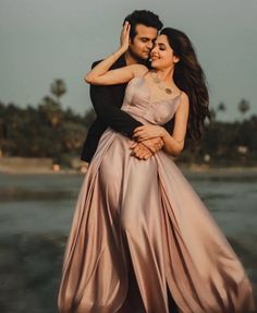 a man and woman hugging each other in front of the ocean