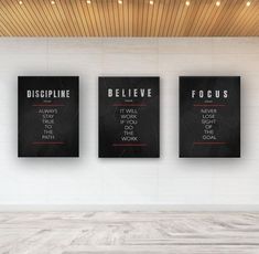 three black and white posters on the wall in an empty room with wood flooring