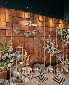 a room filled with vases and flowers next to a wall covered in disco balls