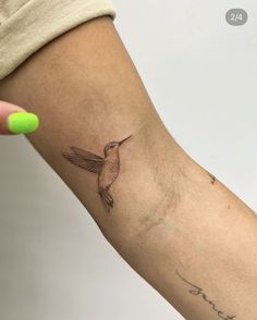 a small hummingbird tattoo on the left inner arm and wrist, with words written in cursive writing