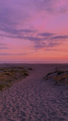 an empty path leading to the beach at sunset or dawn with pink clouds in the sky