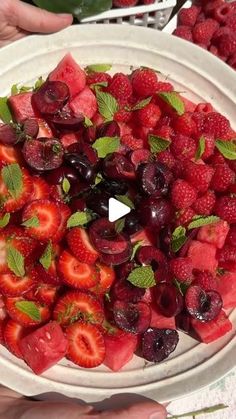 a bowl filled with strawberries and cherries on top of a table