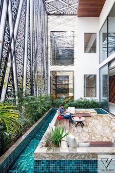 a person sitting on a bench in the middle of a room next to a pool