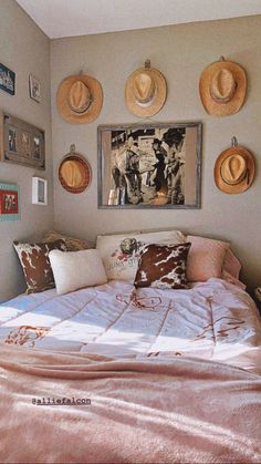 a bed in a bedroom with hats on the wall above it and pictures hanging on the wall