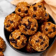 chocolate chip energy bites in a black bowl on a marble countertop next to napkins