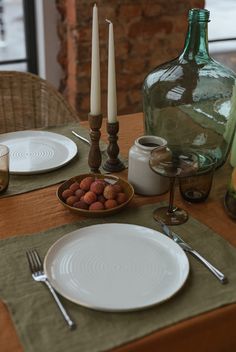 the table is set with plates, silverware, and two tall candlesticks