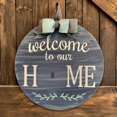 a welcome sign hanging on the side of a wooden fence with two bowknots