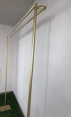 an empty room with green grass on the floor and a gold pole in the corner