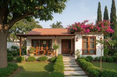 a small white house with lots of flowers on the roof and trees in front of it