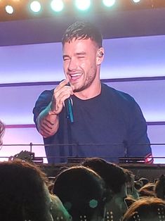 a man standing on top of a stage holding a microphone in front of an audience