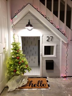 a dog house with a christmas tree in the doorway and lights on it's side