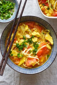 two bowls filled with noodles and vegetables next to chopsticks on top of a table